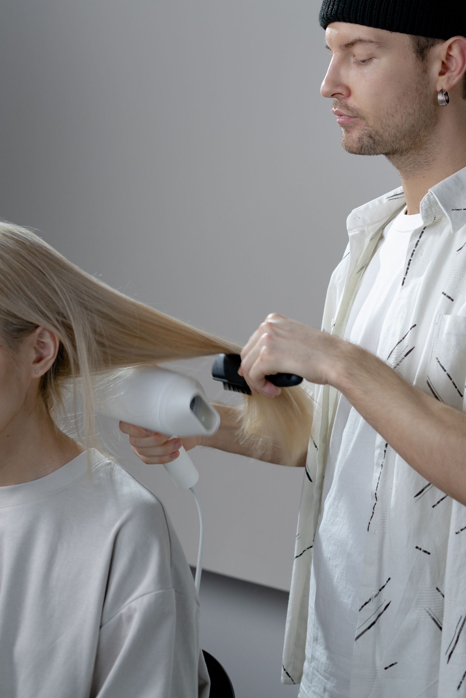 A stylist blow-drying a client's hair at a bright English-speaking hair salon in Busan